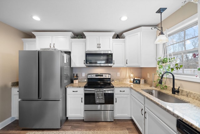 kitchen with white cabinets, dark wood-type flooring, hanging light fixtures, stainless steel appliances, and a sink