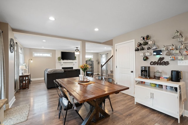 dining space with plenty of natural light, a fireplace, wood finished floors, and stairs