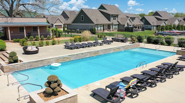 pool with a patio area, a residential view, and fence