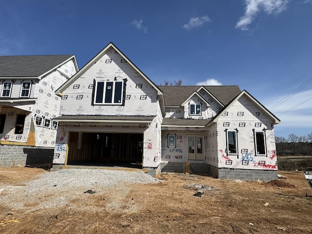 unfinished property featuring a garage and gravel driveway