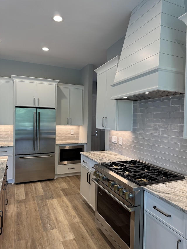 279 Hammock Dr, Winchester, TN 37398 - kitchen with built in appliances, custom range hood, tasteful backsplash, light stone countertops, and light wood-type flooring