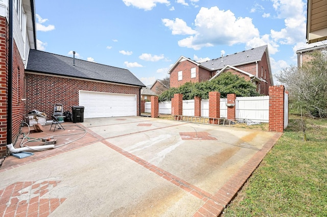 exterior space with a garage, concrete driveway, brick siding, and fence