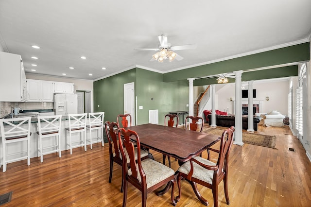 dining room with visible vents, light wood-style flooring, a ceiling fan, and ornate columns