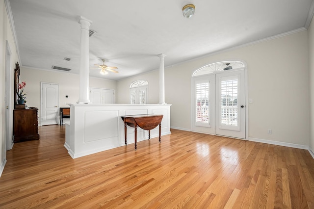 interior space featuring light wood finished floors, decorative columns, visible vents, a ceiling fan, and crown molding