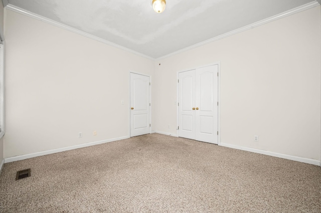 empty room featuring baseboards, carpet flooring, visible vents, and crown molding