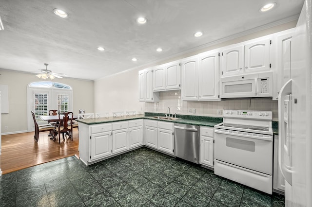 kitchen featuring dark countertops, white cabinets, a sink, white appliances, and a peninsula