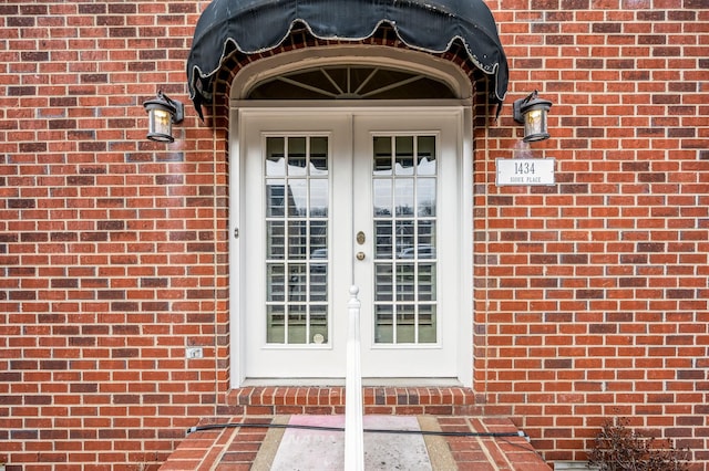 view of exterior entry with brick siding and french doors