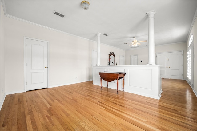 unfurnished living room with decorative columns, visible vents, light wood-style flooring, and crown molding