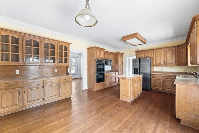 kitchen with dark wood-style floors, glass insert cabinets, light countertops, black appliances, and a sink