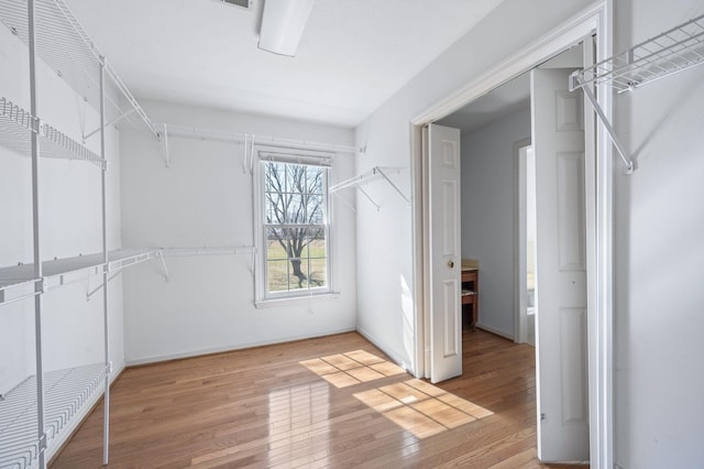 walk in closet with hardwood / wood-style flooring