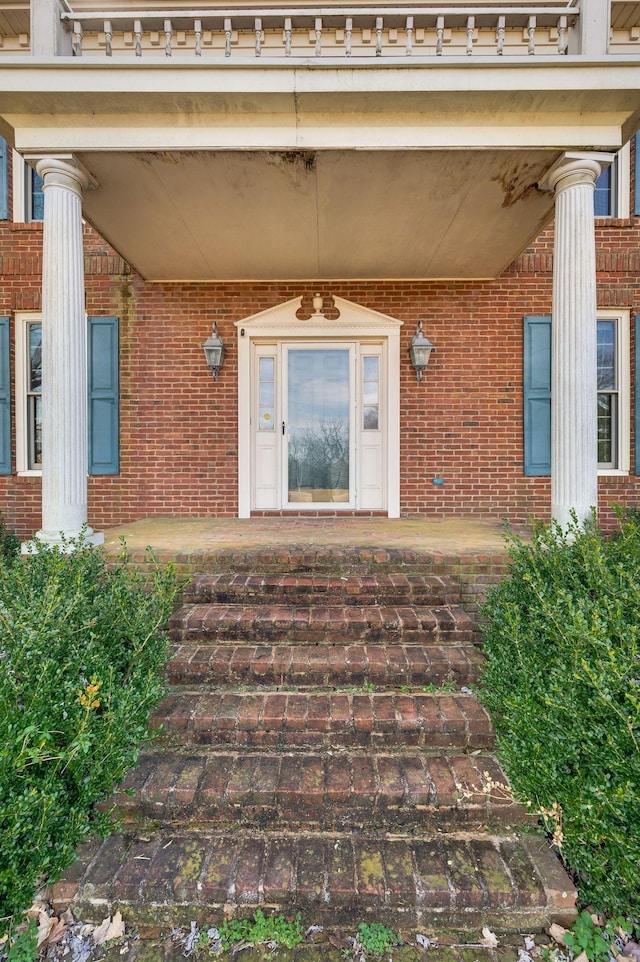 doorway to property featuring brick siding and a porch