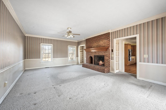 unfurnished living room featuring carpet, crown molding, a brick fireplace, ceiling fan, and baseboards