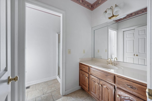 bathroom with a shower with shower door, vanity, baseboards, and tile patterned floors