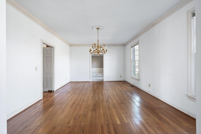 unfurnished room featuring baseboards, crown molding, an inviting chandelier, and wood finished floors