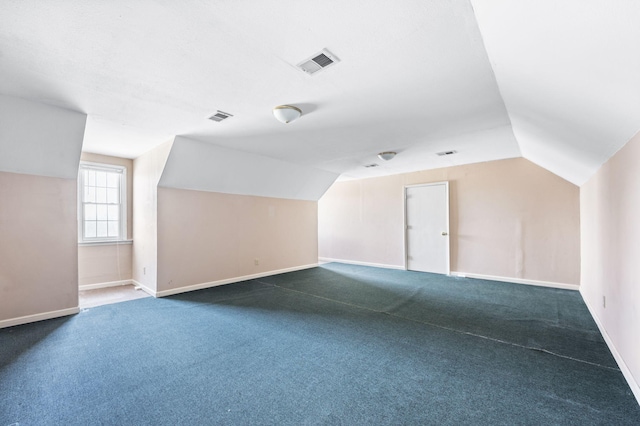 additional living space featuring dark carpet, baseboards, visible vents, and vaulted ceiling