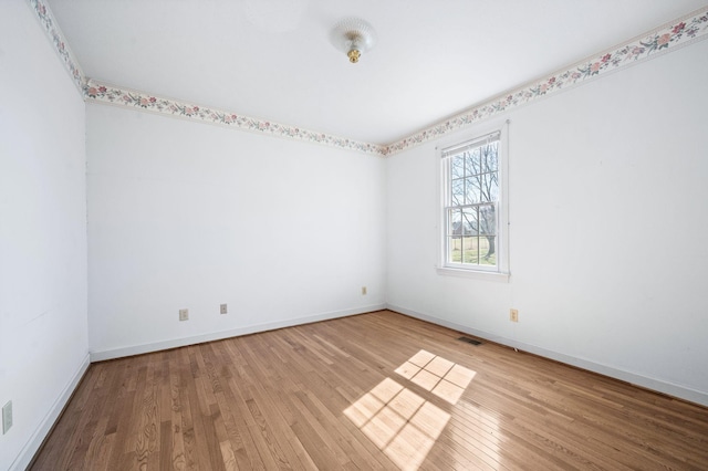 spare room featuring baseboards, visible vents, and hardwood / wood-style floors