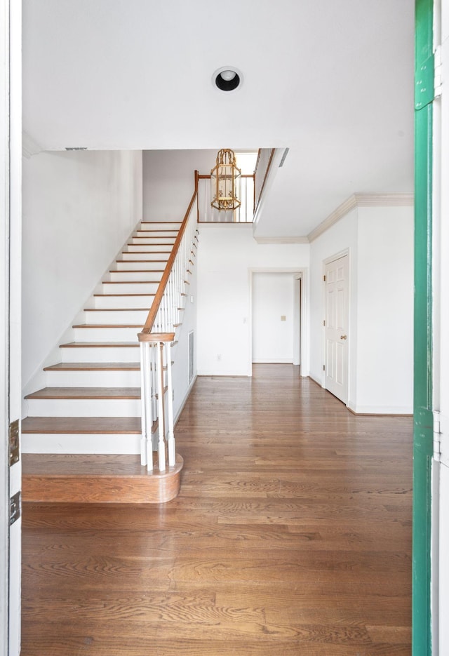 foyer with visible vents, ornamental molding, wood finished floors, stairs, and a notable chandelier