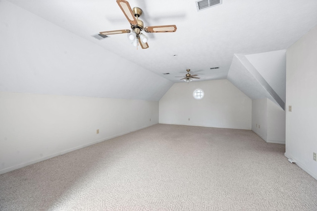 additional living space with a ceiling fan, light colored carpet, visible vents, and vaulted ceiling