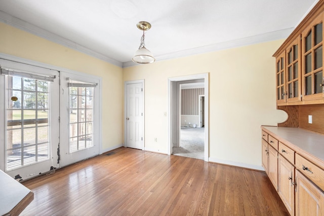 interior space featuring visible vents, ornamental molding, light wood-style flooring, and baseboards