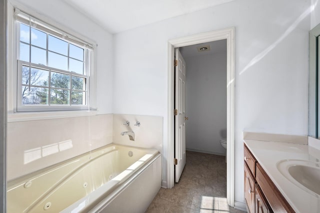 bathroom with a jetted tub, vanity, toilet, and tile patterned floors