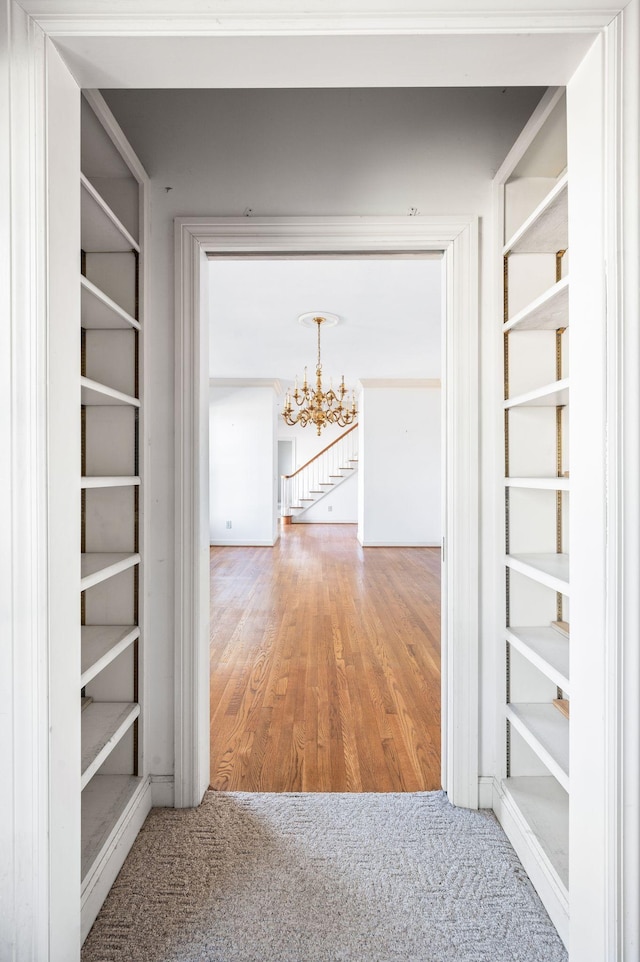 hallway with wood finished floors and a notable chandelier