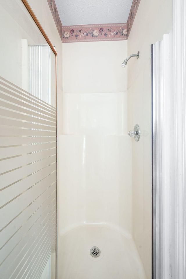 bathroom with a shower stall and a textured ceiling