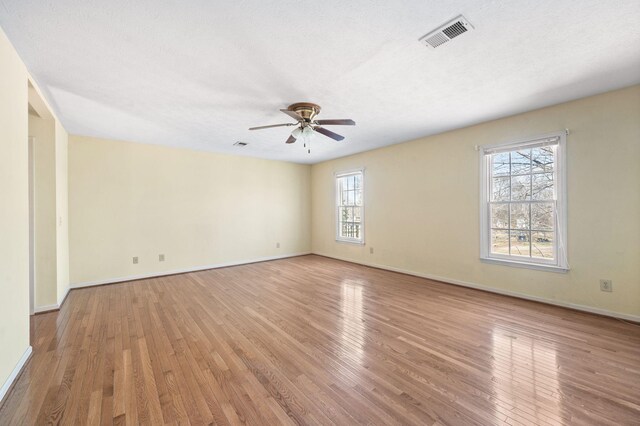 unfurnished room featuring baseboards, visible vents, a ceiling fan, hardwood / wood-style flooring, and a textured ceiling