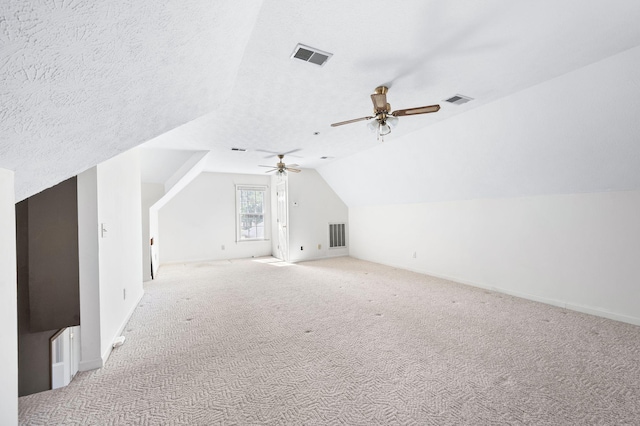 additional living space with light carpet, visible vents, a textured ceiling, and lofted ceiling