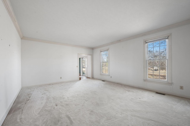 spare room with carpet, visible vents, crown molding, and baseboards