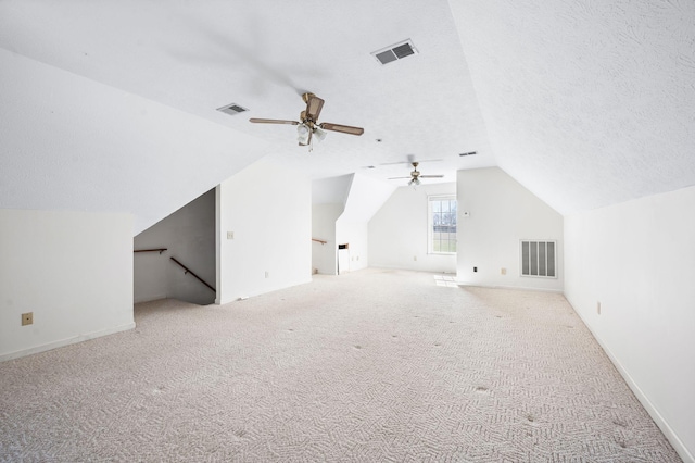 additional living space with carpet, visible vents, vaulted ceiling, and a textured ceiling