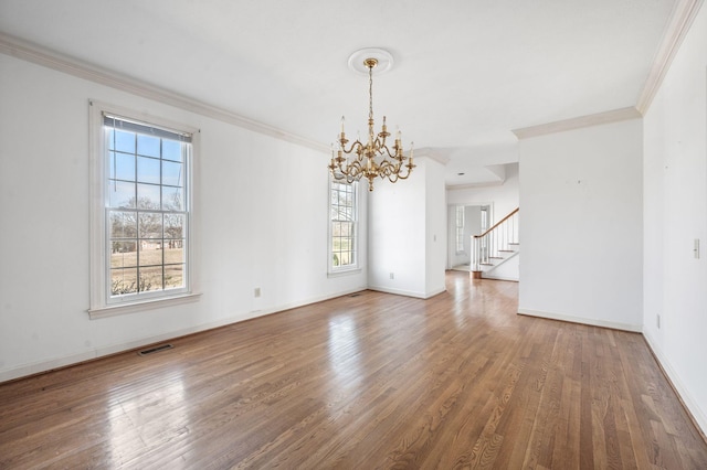 empty room with crown molding, visible vents, and wood finished floors