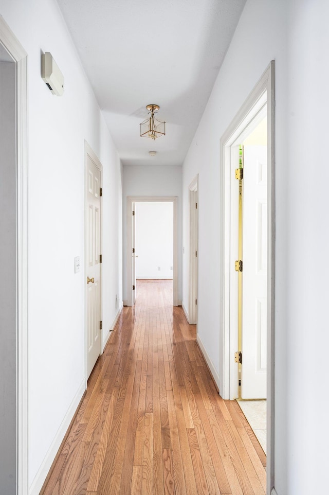 hallway featuring light wood finished floors and baseboards