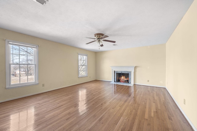 unfurnished living room with baseboards, a ceiling fan, wood finished floors, a textured ceiling, and a high end fireplace