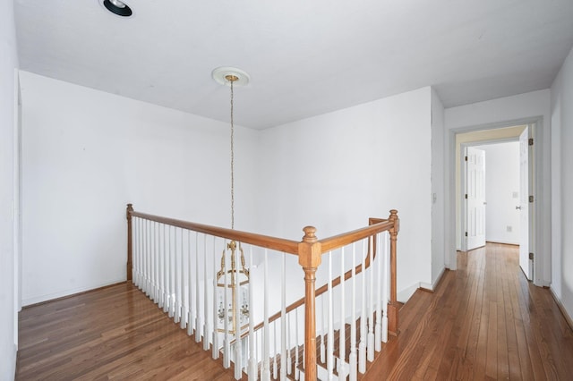 corridor featuring a chandelier, baseboards, an upstairs landing, and wood finished floors