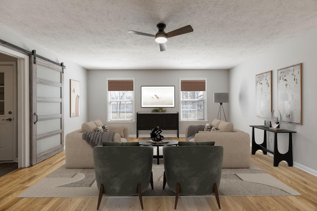 living area with a barn door, a textured ceiling, ceiling fan, and wood finished floors