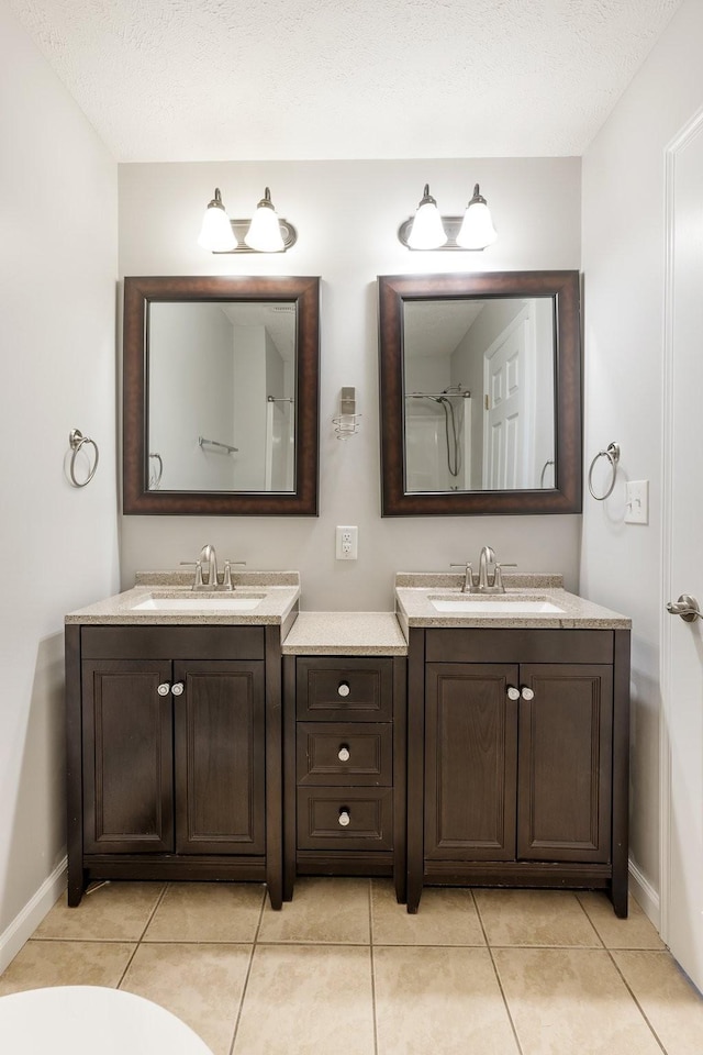 full bathroom featuring tile patterned floors, baseboards, a textured ceiling, and vanity