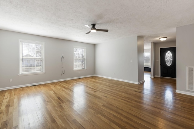 unfurnished living room with visible vents, plenty of natural light, and hardwood / wood-style flooring