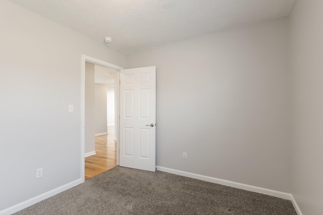 spare room featuring light carpet and baseboards