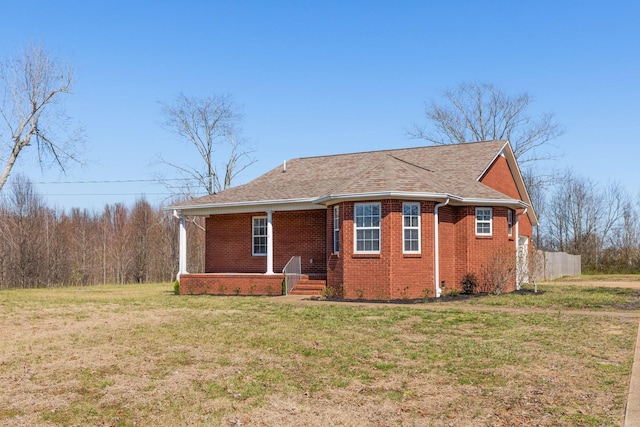 exterior space with roof with shingles, brick siding, and a lawn