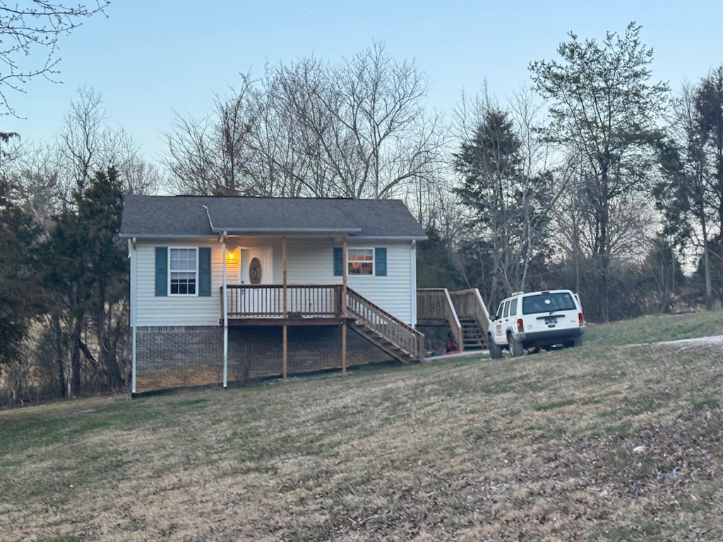 ranch-style house featuring a porch, stairs, a front lawn, and brick siding