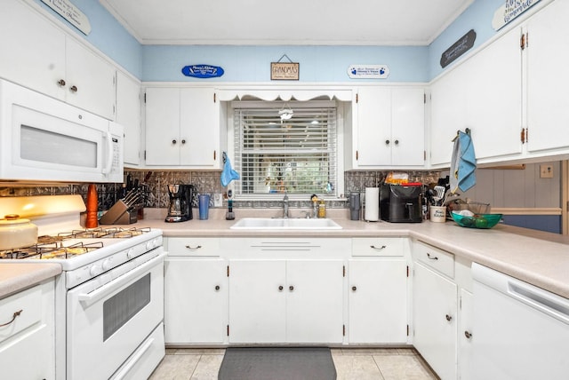 kitchen with white appliances, backsplash, a sink, and white cabinets