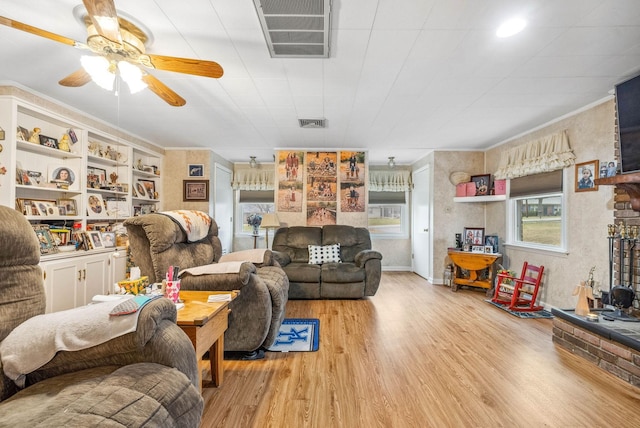 living area with ceiling fan, ornamental molding, wood finished floors, and visible vents