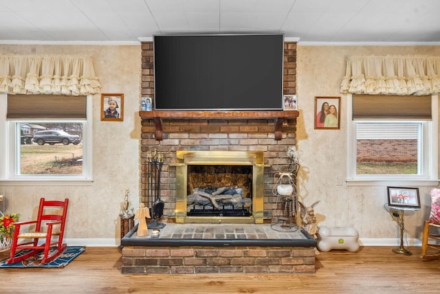 living area with crown molding, a fireplace, and wood finished floors