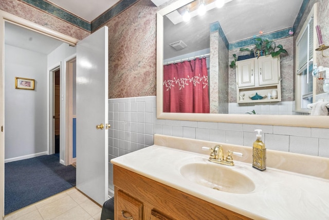 full bath featuring tile walls, wainscoting, vanity, tile patterned flooring, and wallpapered walls