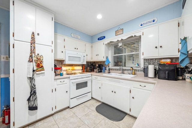 kitchen with white appliances, backsplash, light countertops, and a sink