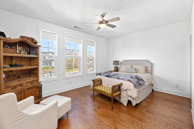 bedroom with ceiling fan, wood finished floors, visible vents, and baseboards