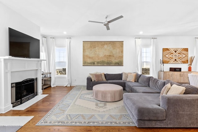 living area featuring ceiling fan, dark wood-type flooring, a fireplace with flush hearth, and recessed lighting