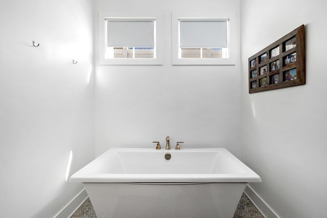 full bathroom featuring a freestanding tub and baseboards