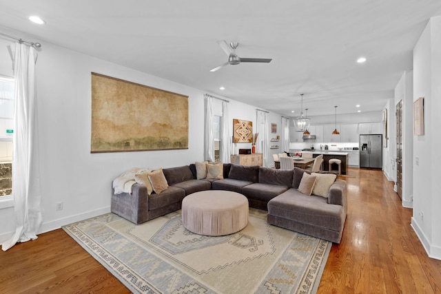 living area with ceiling fan with notable chandelier, recessed lighting, and wood finished floors