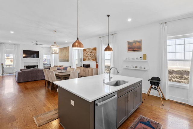 kitchen with a fireplace, visible vents, a sink, wood finished floors, and dishwasher